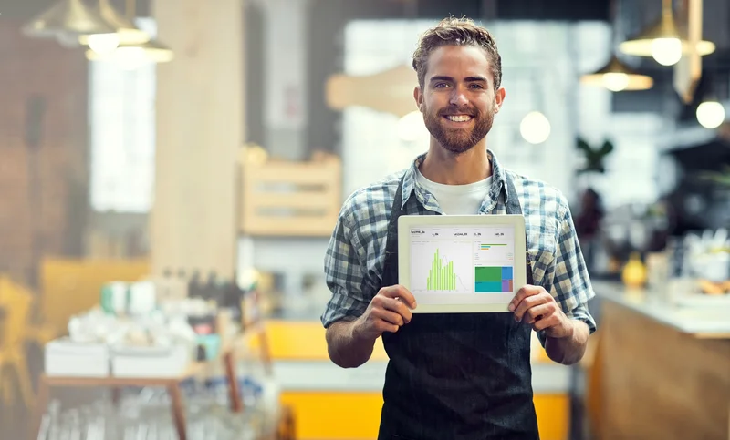 Barista in a modern café with analytics tablet on the counter